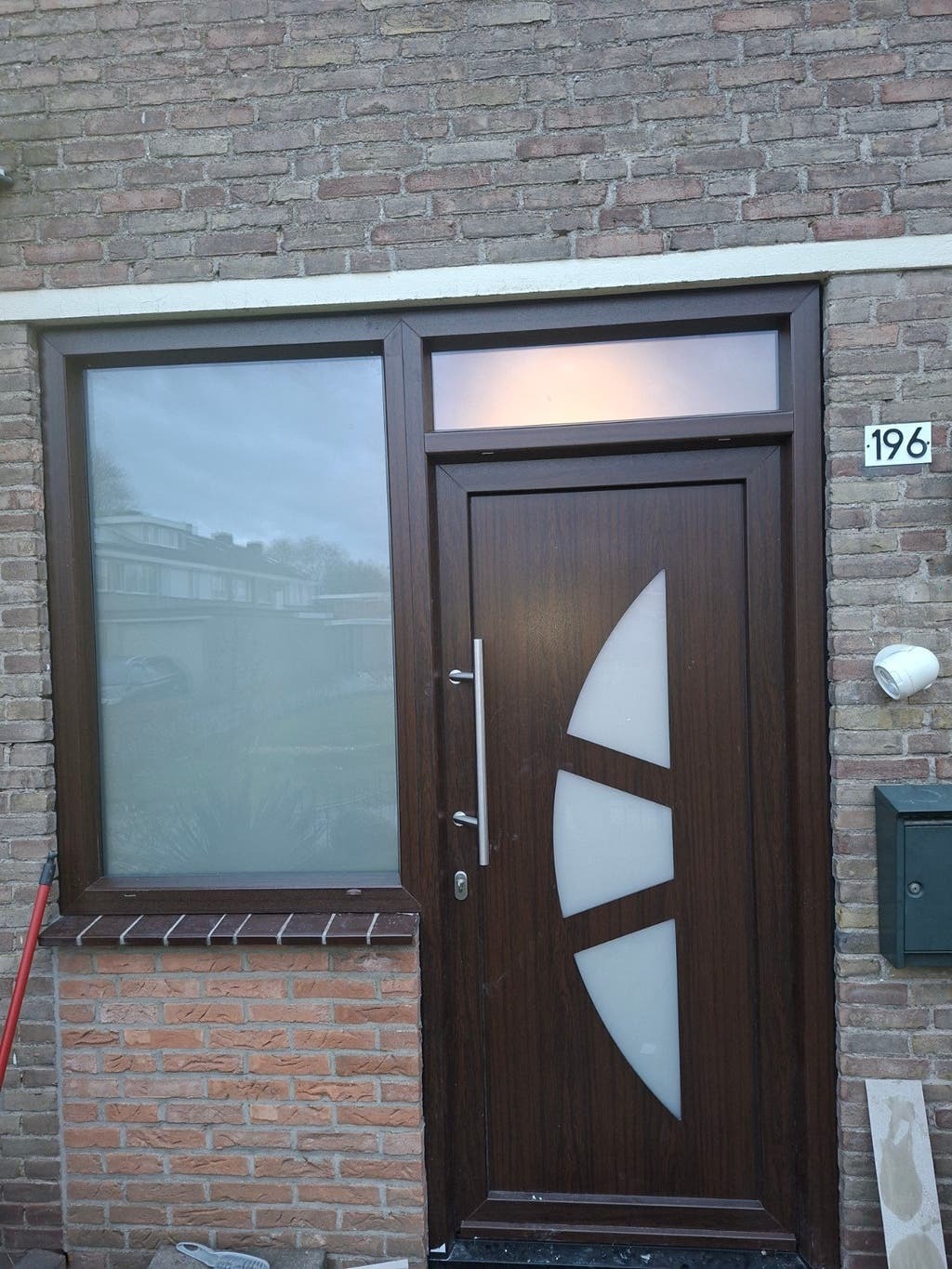 Kozijn en voordeur met bovenlicht in een bakstenen gevel