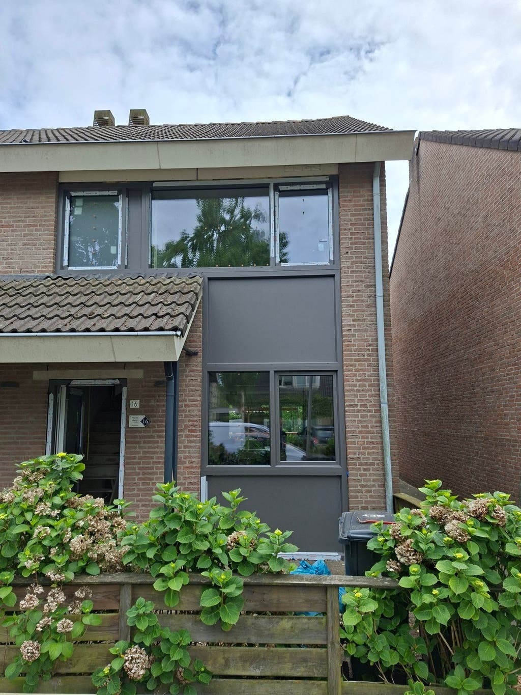 Antracietkleurige kozijnen en rolluik in een woninggevel, uit de advertentie